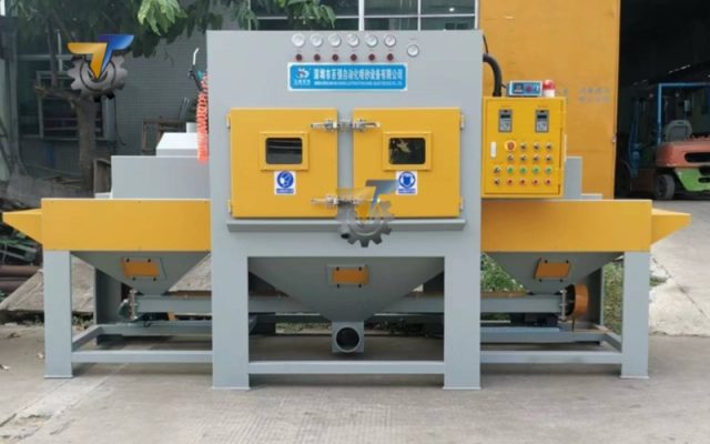 Máy phun cát dạng băng tải là gì?